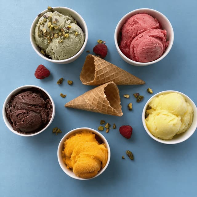 Cups of gelato and sorbet from above on pastel blue — gelateria food photography