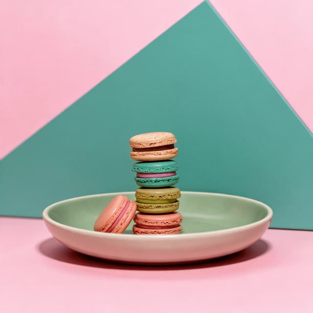 Stack of pastel French macarons on a pink studio set — patisserie food photography