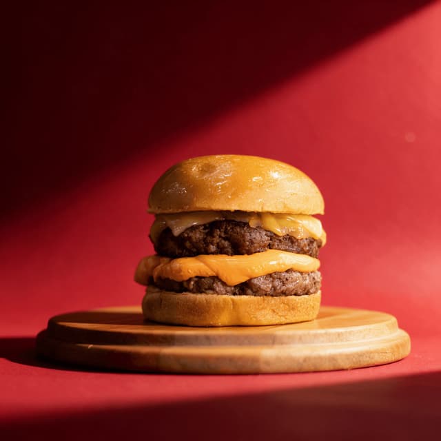 Double cheeseburger on a wooden board against red — limited-time offer fast food photography