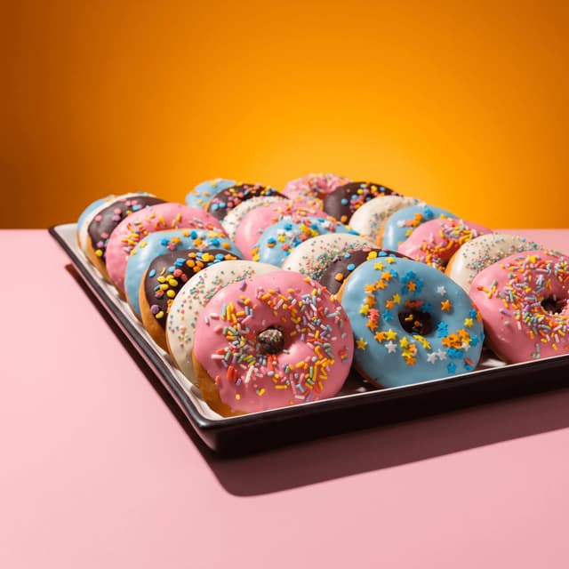 Assorted glazed donuts on a tray on pastel pink — bundle deal poster food photography
