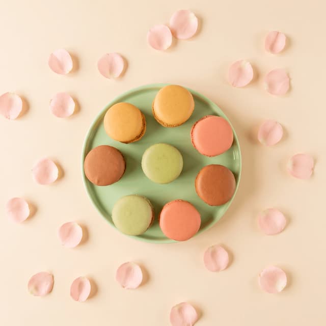 Pastel macarons on a mint plate with rose petals from above — social media food photography