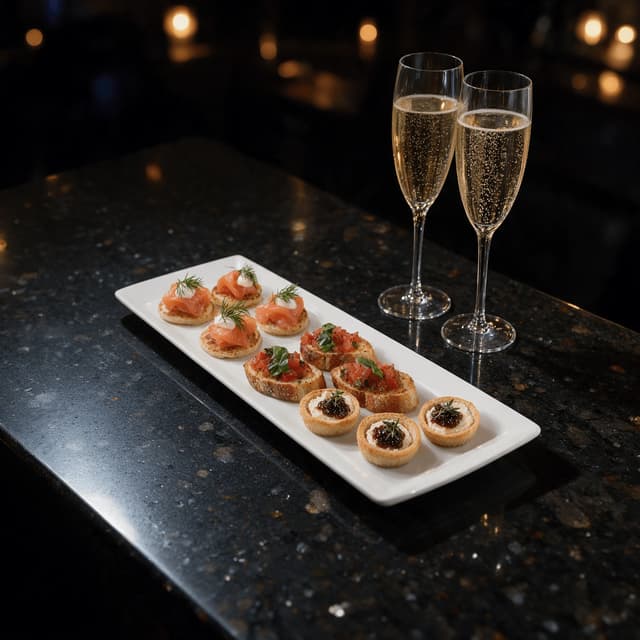 Canapés and sparkling wine flutes on dark granite — banquet event food photography