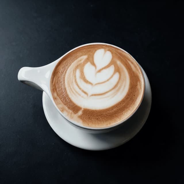 Cappuccino with latte art on a charcoal table — hotel lounge coffee photography