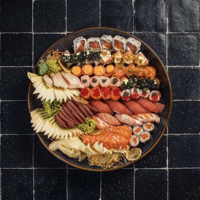 Sushi and sashimi platter on black tile — sushi bar website banner food photography