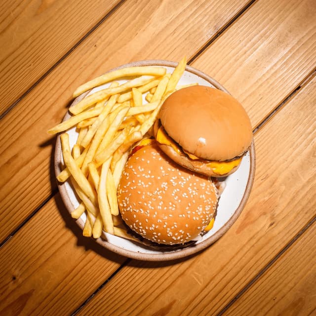 Two cheeseburgers and fries on honey wood planks — online ordering header food photography