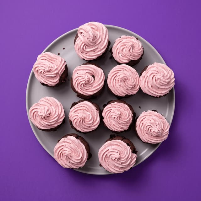 Chocolate cupcakes with strawberry buttercream on violet — brand color banner food photography
