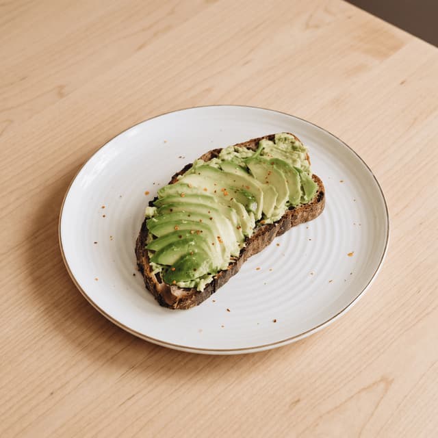 Avocado toast with chili flakes on light maple — cafe website banner food photography