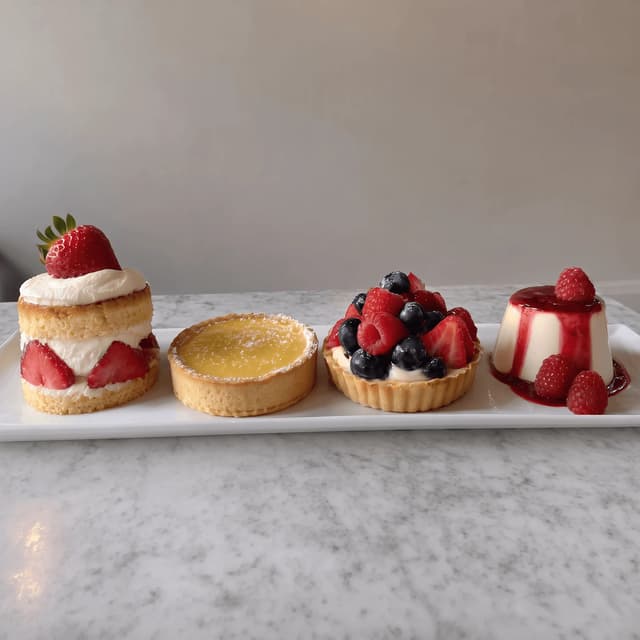 Four summer desserts in a row on white marble — seasonal campaign food photography