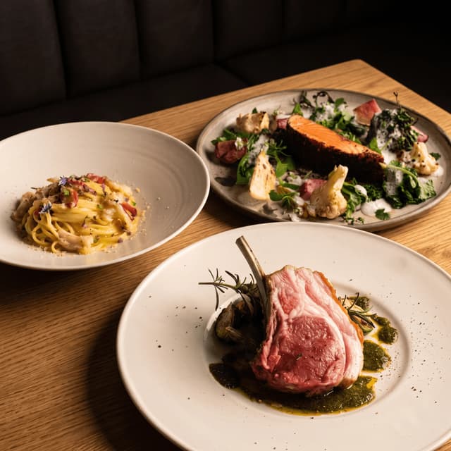 Rack of lamb, salmon and pasta on an oak table — dinner menu food photography