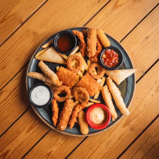 Fried bar snack platter with onion rings and dips on pine — gastropub food photography