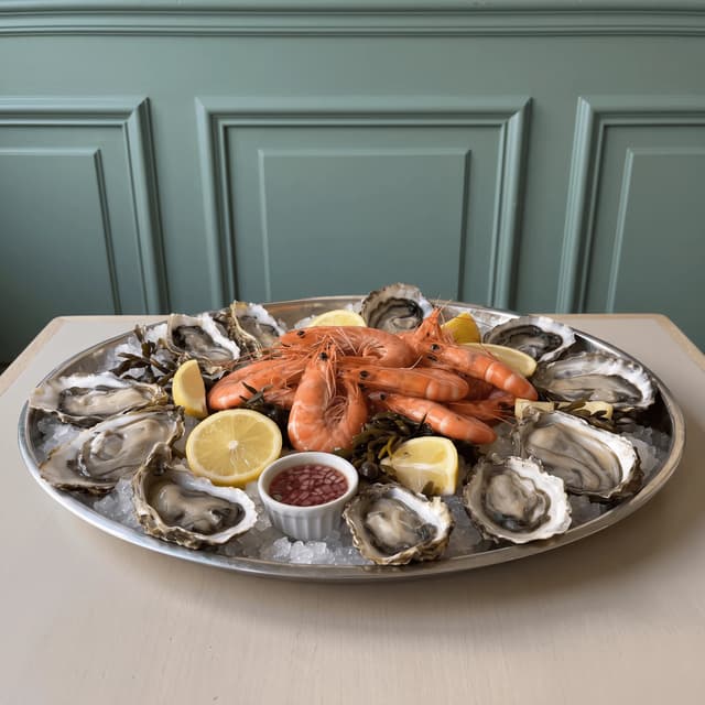 Oysters and prawns on crushed ice in a steel platter — seafood menu food photography