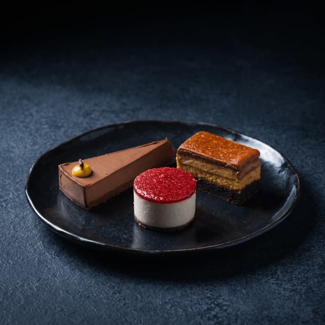 Chocolate tart, raspberry mousse and caramel cake on dark slate — dessert food photography