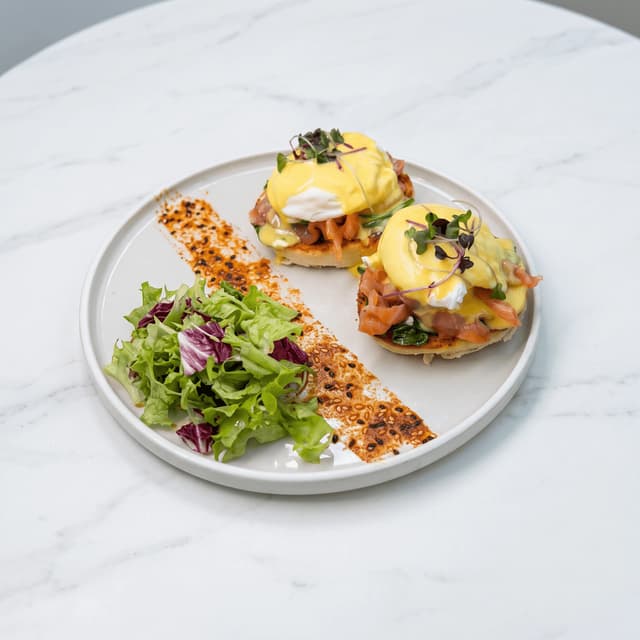 Eggs Benedict with smoked salmon and hollandaise on white marble — brunch menu food photography
