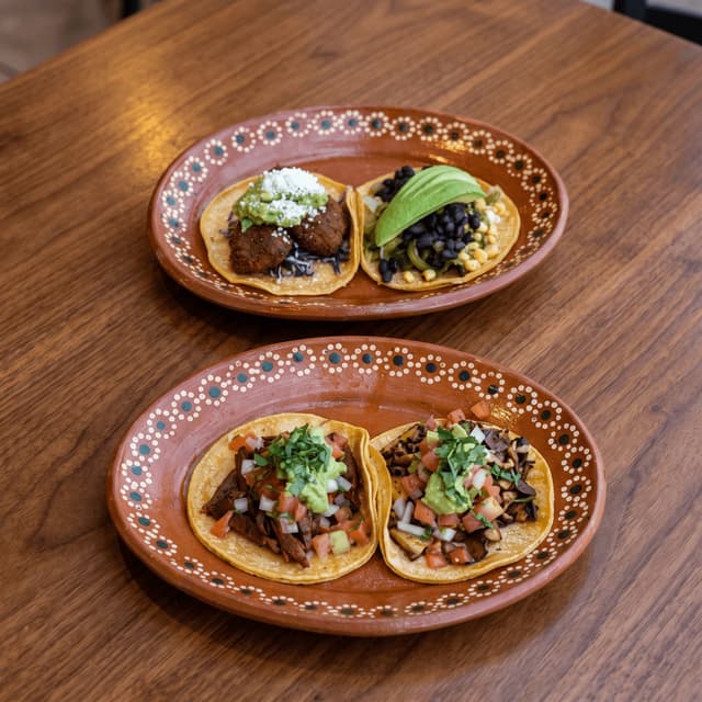 Four street tacos on Mexican clay plates on walnut — weekly stops flyer photography