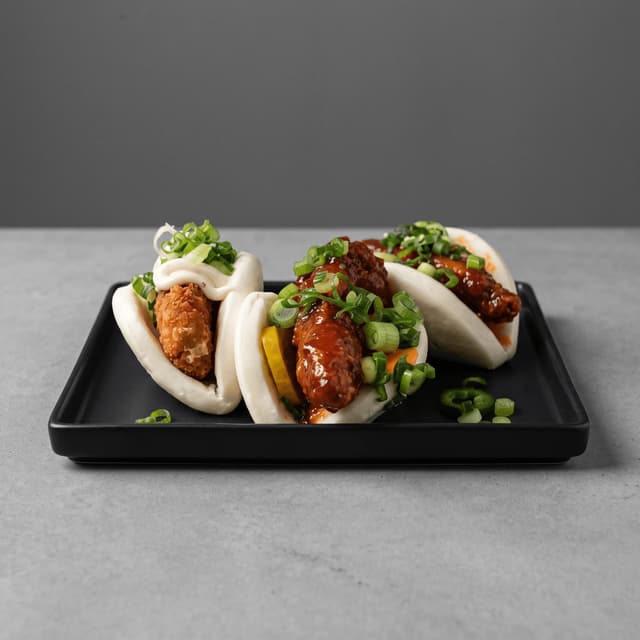 Fried chicken bao on a black tray on gray concrete — fusion flyer food photography