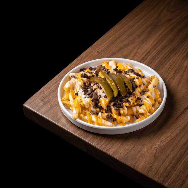 Loaded fries with cheese sauce, steak and jalapeños on dark wood — truck flyer photography