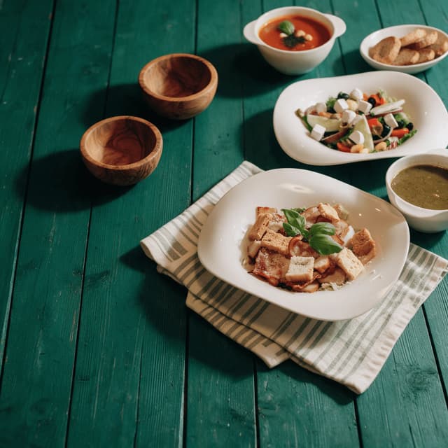 Tomato soup, Greek salad and Caesar salad on teal planks — lunch menu food photography