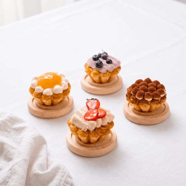 Apricot, blueberry, tiramisu and strawberry pastry tarts on white linen — patisserie product photography