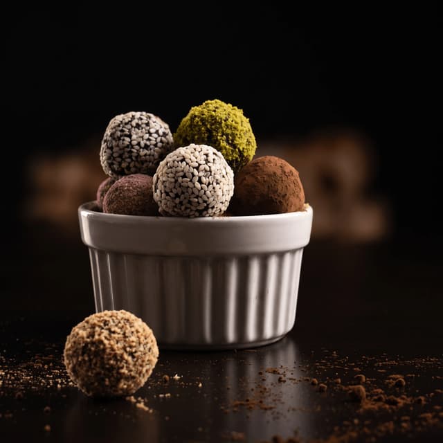 Sesame, pistachio and cocoa truffles in a white ramekin — chocolate maker product photography