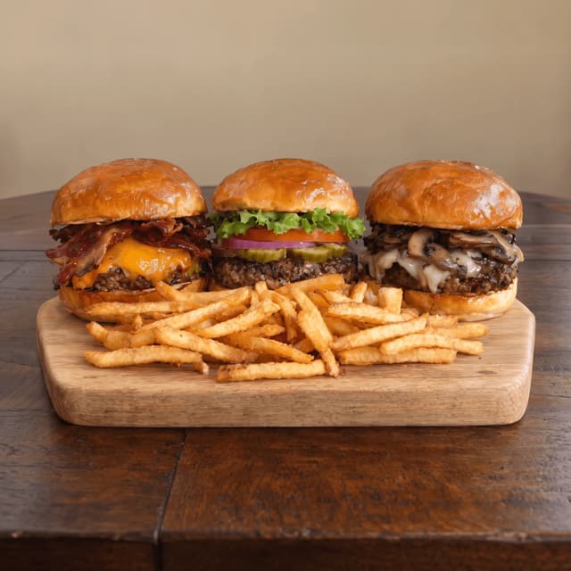 Bacon, classic and mushroom burgers with fries on a walnut table — burger ad photography