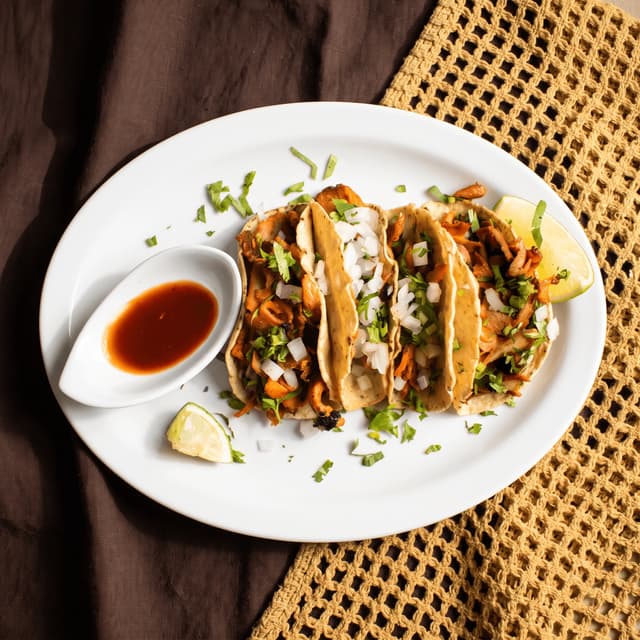 Al pastor tacos with salsa roja and lime on woven cloth — Taco Tuesday ad photography