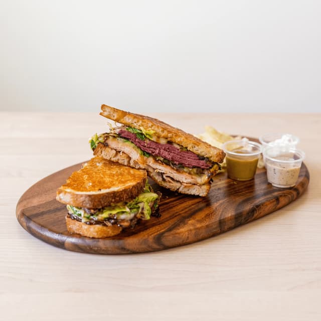 Griddled pastrami sandwich with chips on a walnut board — lunch specials flyer photography