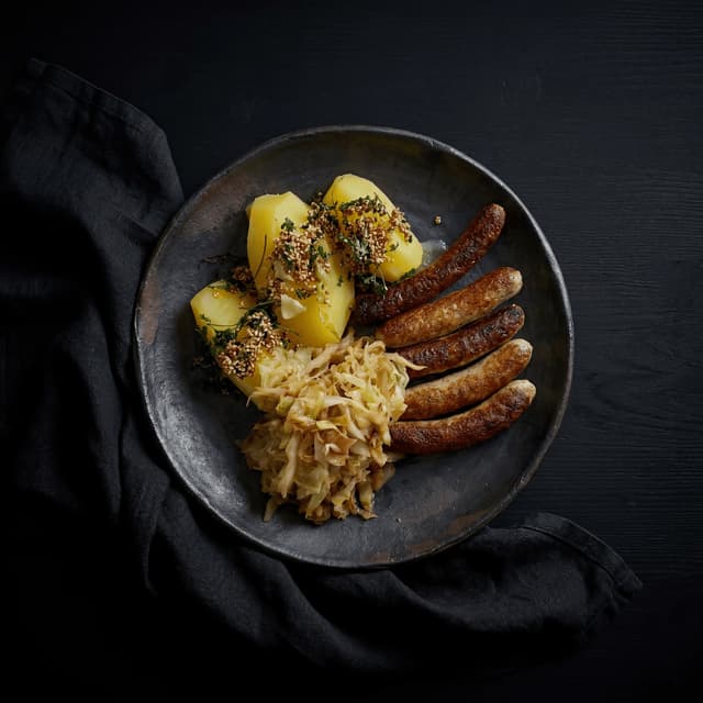 Post-oak smoked original hot link cluster with jalapeño cheese sausage and white bread on checkered butcher paper — Central Texas smokehouse photography