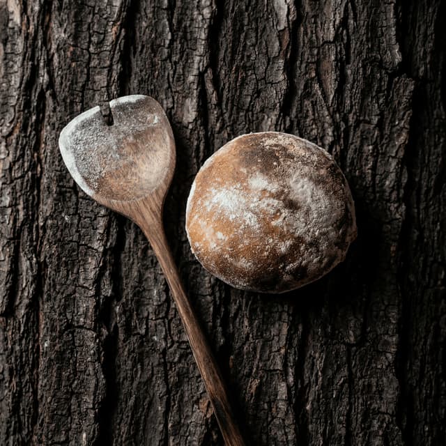 French signed miche sourdough wheel with P-score and wheat flour dusting on oak plank — bakery bread photography