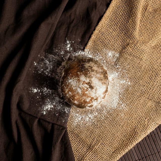 Fresh country miche with visible oven steam on flour-dusted linen — artisan bread photography