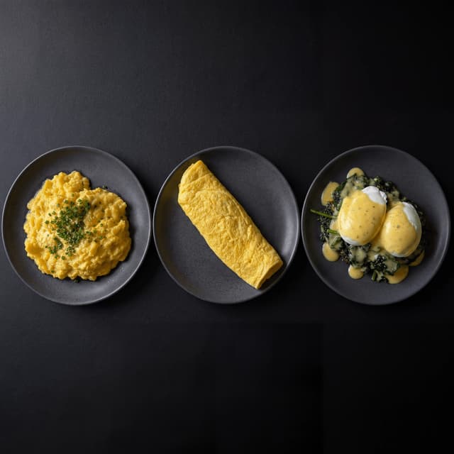 Three egg preparations scramble omelet poached dark monolith — egg dishes card photography