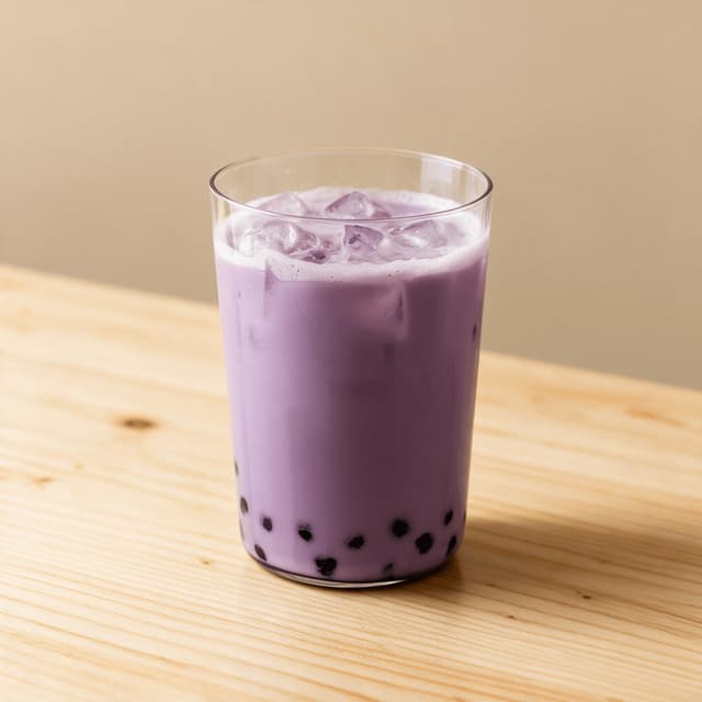 Iced taro milk tea in a clear glass showing a smooth pale purple body over a bed of dark tapioca pearls