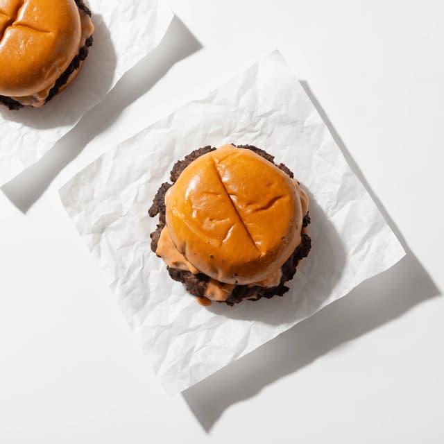 Classic smash burger American cheese lettuce tomato parchment paper — fast food burger hero photography