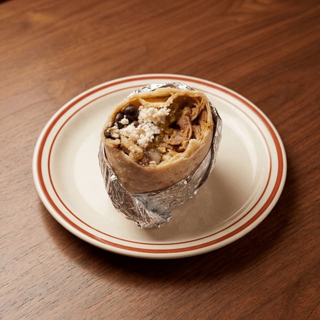 Hand-held foil-wrapped Mission burrito carne asada cheese rice exposed — Mexican fast casual hero photography