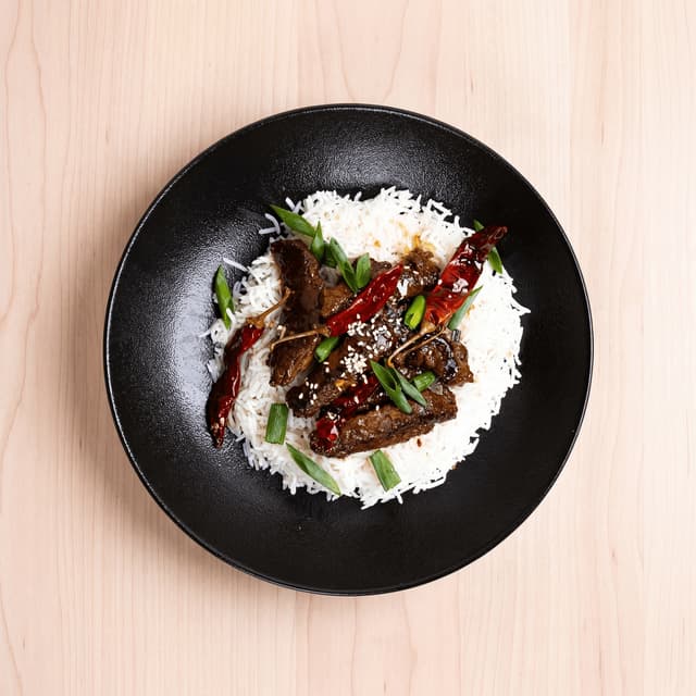 Korean dosirak lunch box with bulgogi, japchae, and banchan compartments — corporate catering photography