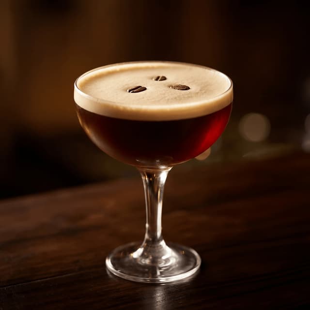 Espresso martini foam top three espresso beans crystal coupe — cocktail hero photography