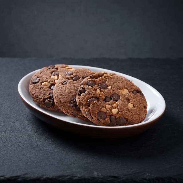 Oversized chocolate chip walnut cookie with molten gooey center — American bakery cookie photography
