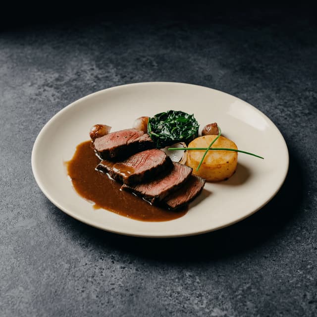 Sliced côte de boeuf with red wine jus and bone marrow — dramatic YouTube thumbnail food photography