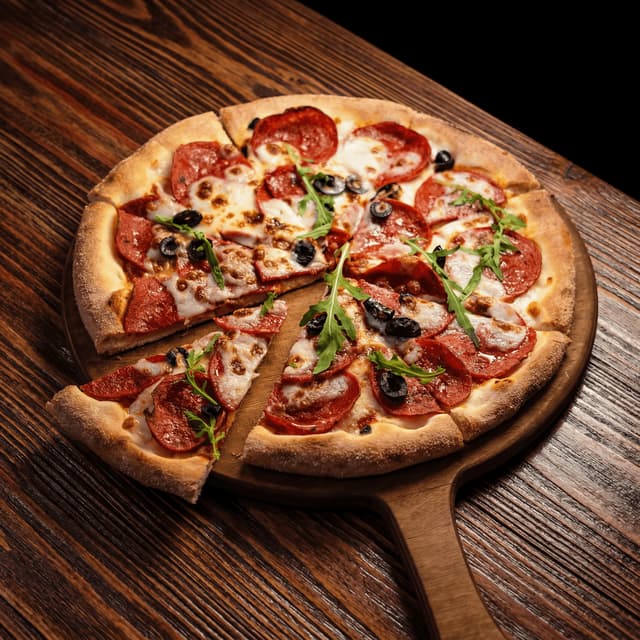 Pepperoni-pizza med ruccola og sorte oliven på treskyffel — matfotografering for ghost kitchen pizza-merke