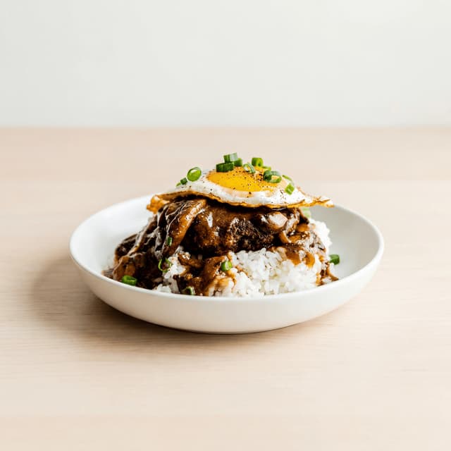 Loco moco rice hamburger patty egg gravy plate light wood — loco moco hero photography
