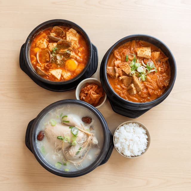 Korean stews soondubu samgyetang kimchi jjigae ttukbaegi pots overhead light wood — stew card photography