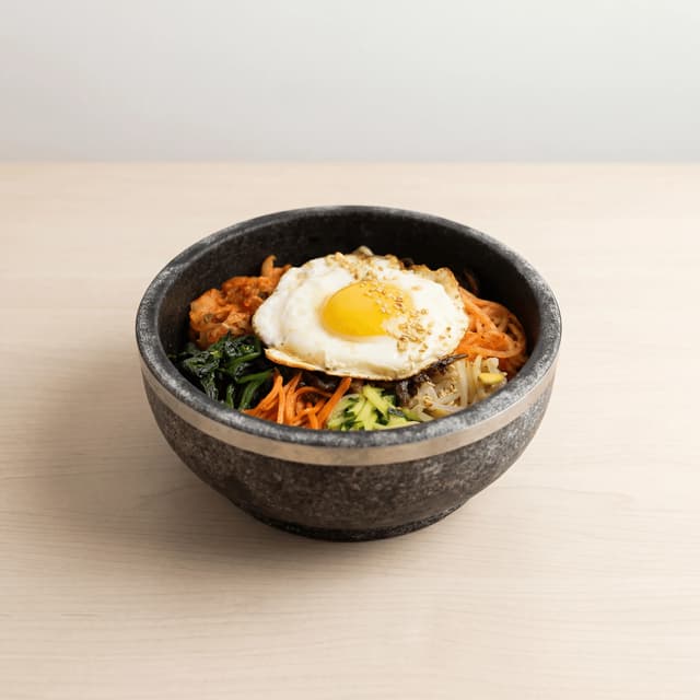 Dolsot bibimbap stone bowl egg yolk gochujang vegetables crispy rice sesame — bibimbap hero photography