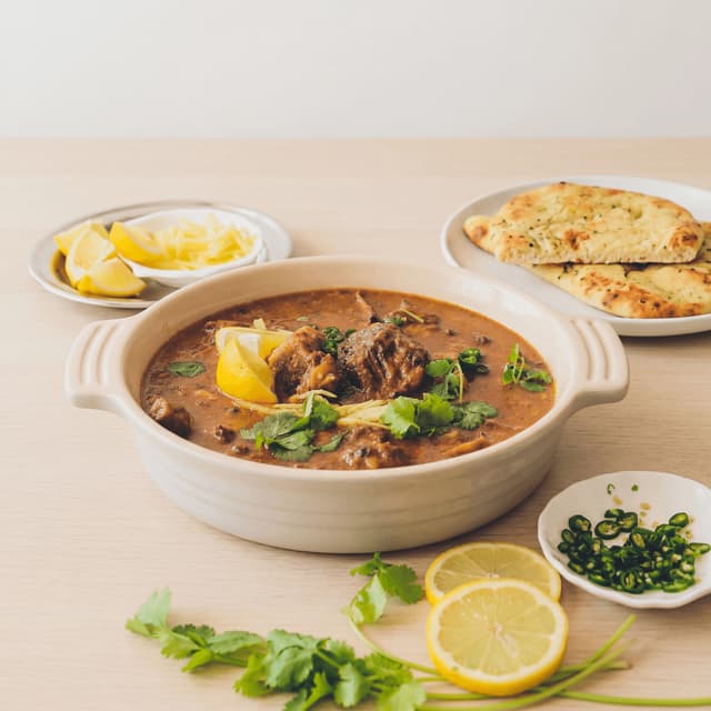 Nihari beef shank bone marrow rich red brown gravy ginger lime fried onion bowl — nihari hero photography