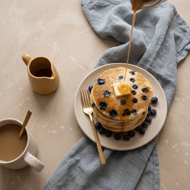 Wieża maślankowych pancakes z borówkami i syropem klonowym oraz kostką masła — bohaterska fotografia pancakes z jadłodajni