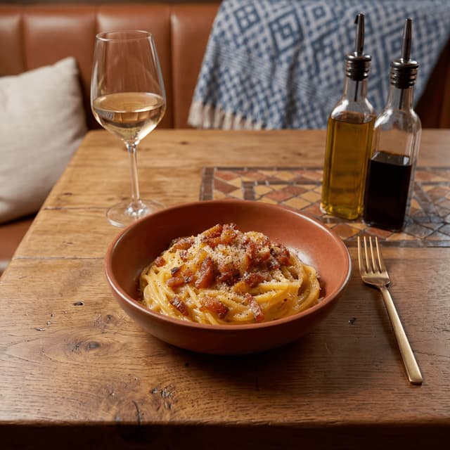 Spaghetti carbonara twirled on fork with crispy guanciale and cracked pepper — Italian trattoria pasta hero photography