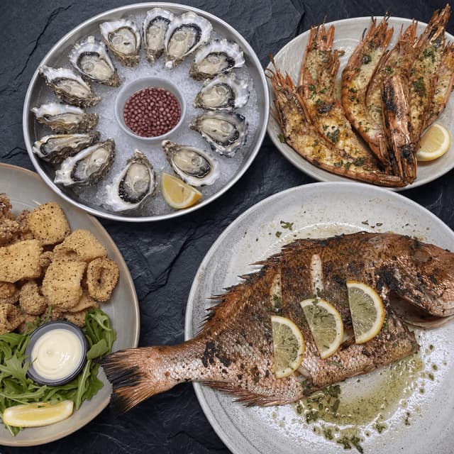 Fremantle seafood østers chargrillede rejer hel snapper salt peber blæksprutte mørk skifer ovenfra Perth — seafood card-fotografering