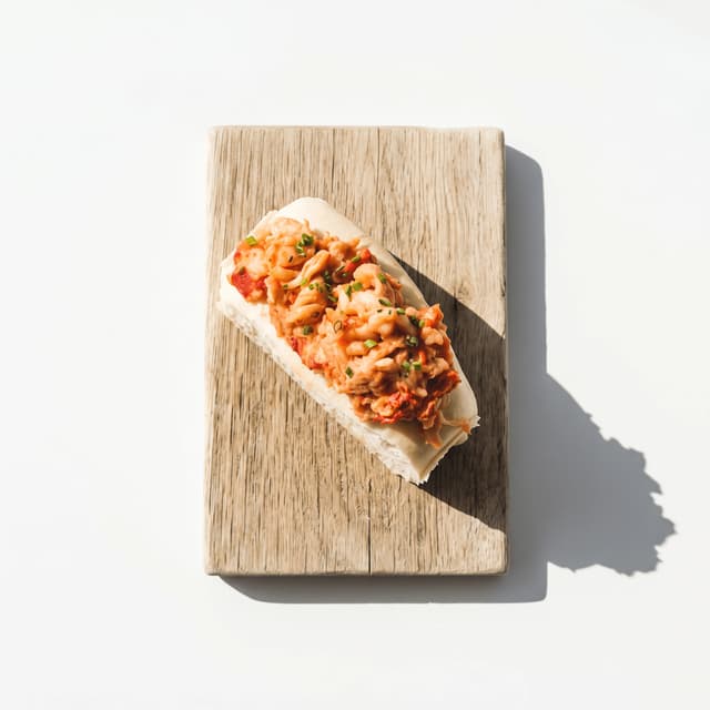 Maine lobster roll toasted brioche bun butter chunks — New England seafood hero photography