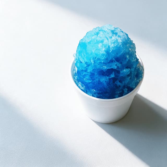 Single white foam cup packed with electric blue raspberry snow cone ice, syrup soaking down through the crystals