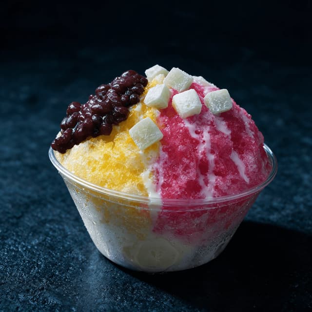 Wide cup of shave ice built over vanilla ice cream and topped with soft mochi and sweet red beans
