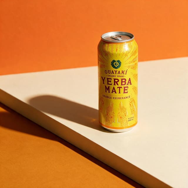 Yerba mate can on cream plinth against orange color-block backdrop with hard shadow — editorial beverage photography
