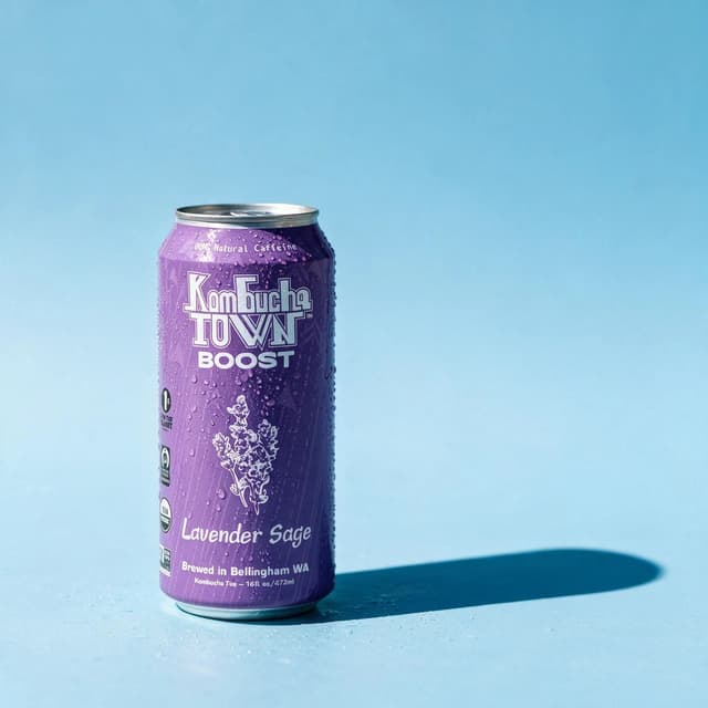 Kombucha can in soft pastel sunlight against a sky-blue backdrop — minimal beverage product photography
